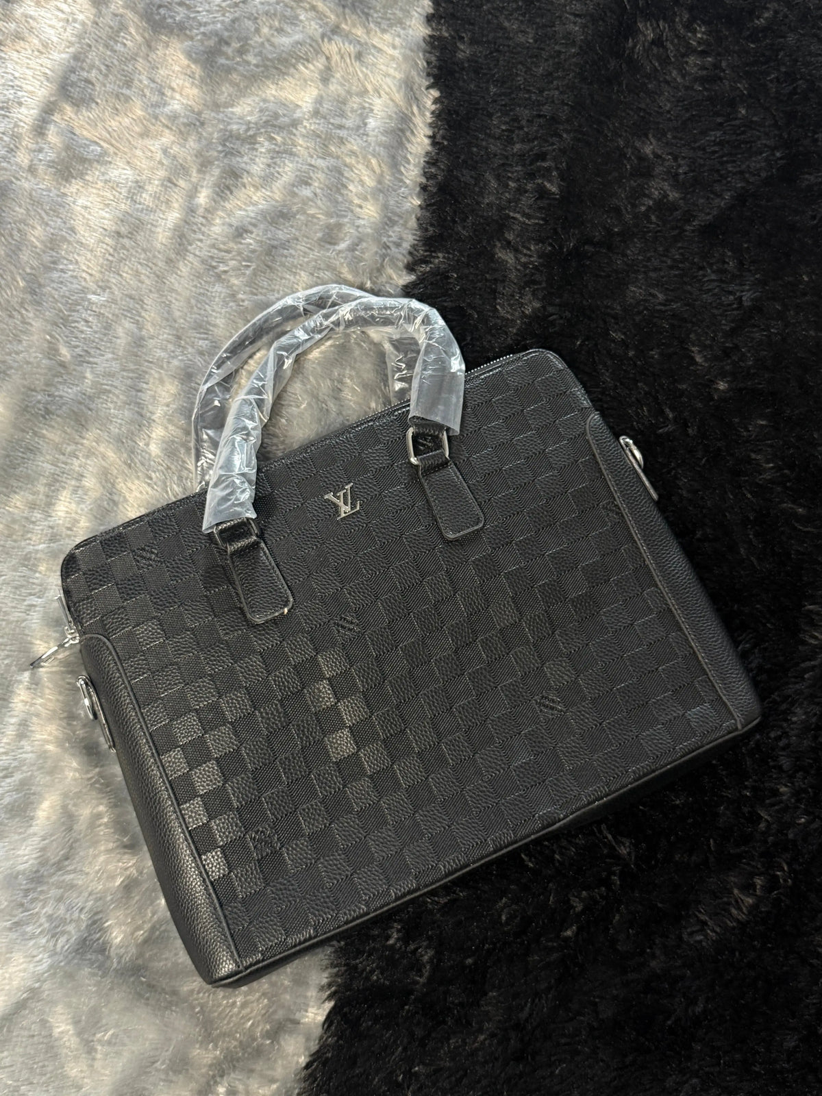 Louis Vuitton Damier Graphite laptop bag features a black checkered pattern and a prominent silver LV logo