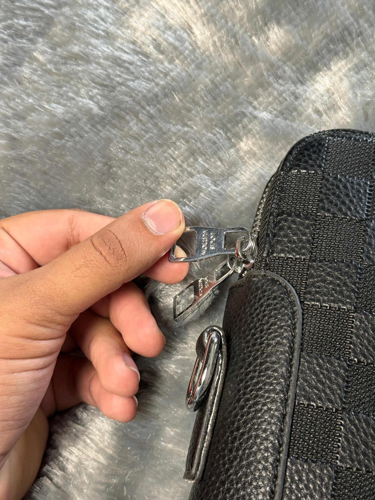 Louis Vuitton Damier Graphite laptop bag features a black checkered pattern and a prominent silver LV logo