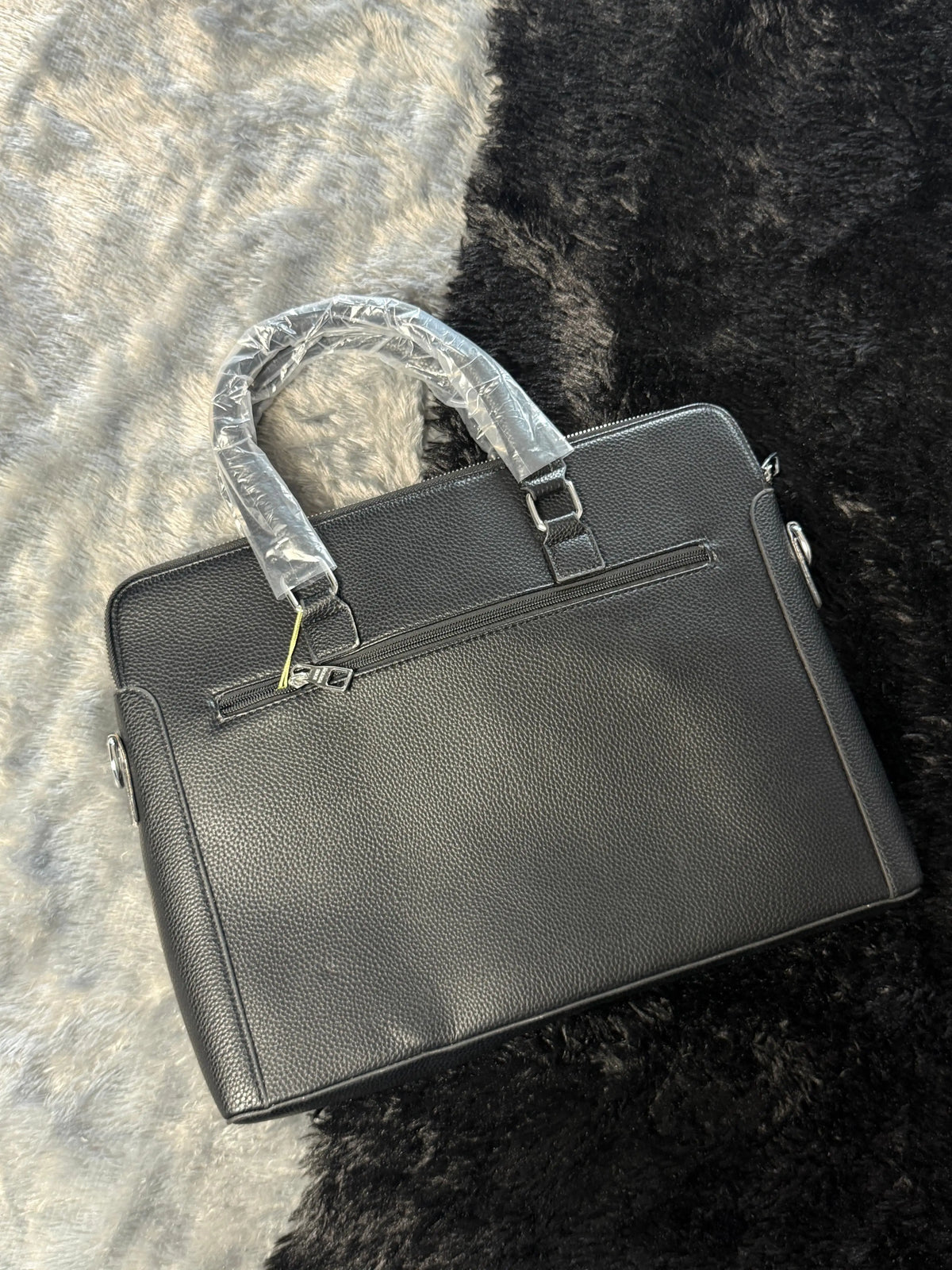 Louis Vuitton Damier Graphite laptop bag features a black checkered pattern and a prominent silver LV logo